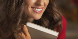 Closeup on woman with christmas cup of chocolate hugging book
